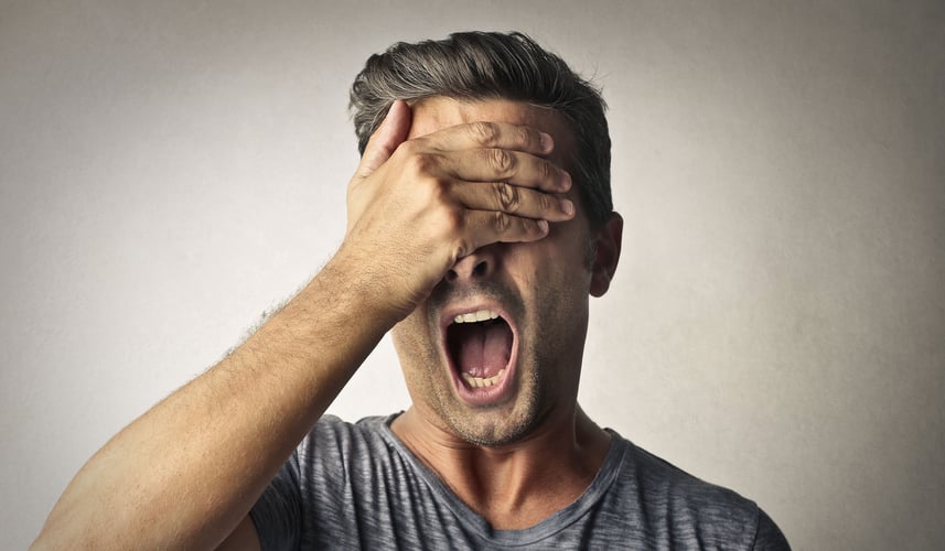 Man screaming with his hands over his eyes.