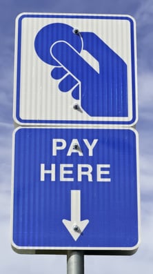 Tall blue and white sign in parking lot PAY HERE