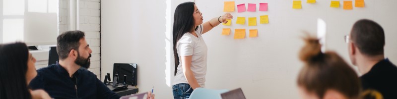 Team of people looking at whiteboard with post its