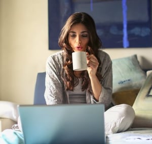 Woman using laptop drinking coffee