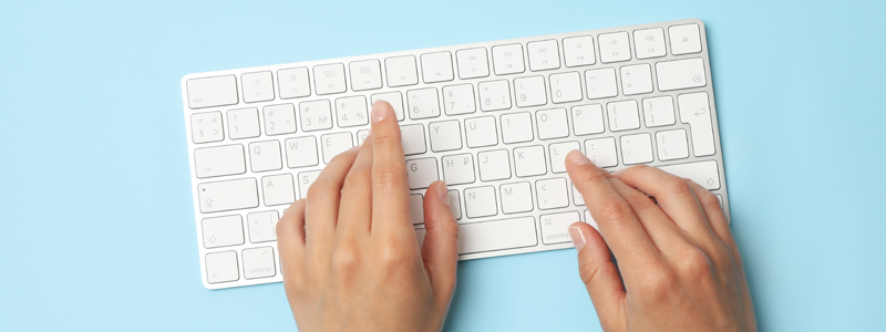 Woman typing on keyboard with blue background.