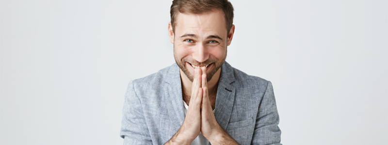 Man in business suit holding hands together under his chin.